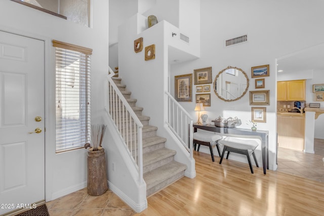 foyer entrance with a towering ceiling and light hardwood / wood-style flooring