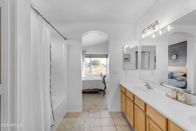 bathroom with shower / tub combo, vanity, vaulted ceiling, and tile patterned flooring