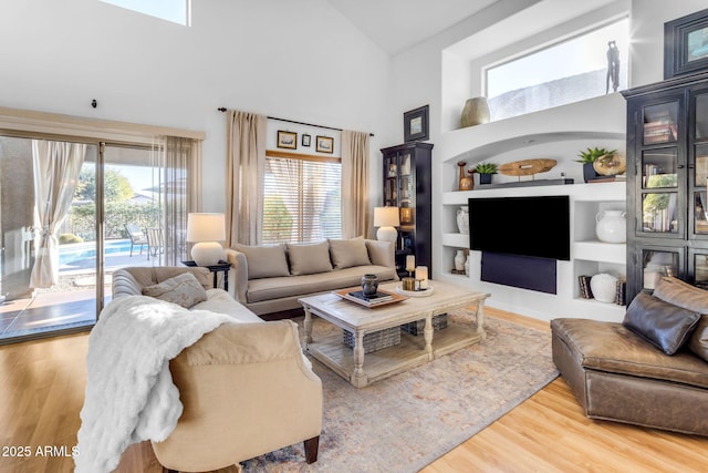 living room featuring a high ceiling, wood-type flooring, and built in features