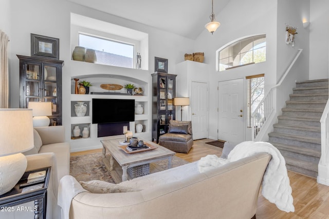 living room with a towering ceiling, light hardwood / wood-style flooring, and built in features