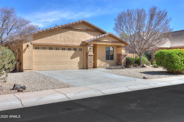 view of front of house featuring a tiled roof, concrete driveway, stucco siding, a garage, and stone siding