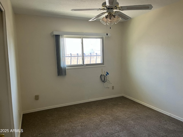 empty room with dark colored carpet, ceiling fan, a textured ceiling, and baseboards