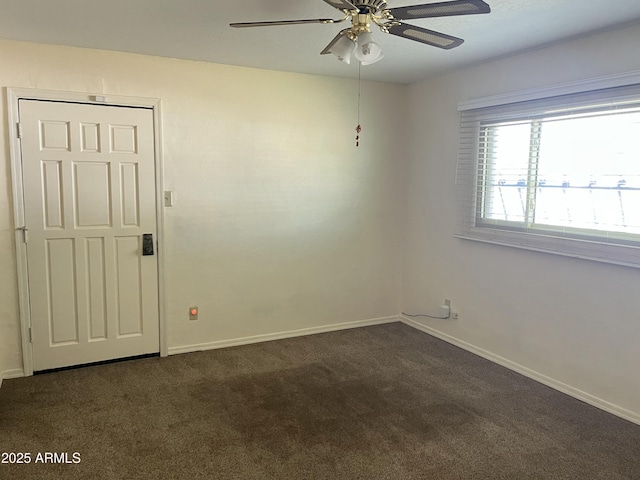 unfurnished room featuring a ceiling fan, dark carpet, and baseboards