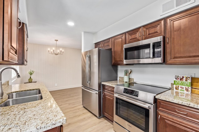 2015 E Southern Ave Unit 16, Tempe, AZ 85282 - kitchen with appliances with stainless steel finishes, light wood-type flooring, a chandelier, light stone counters, and pendant lighting