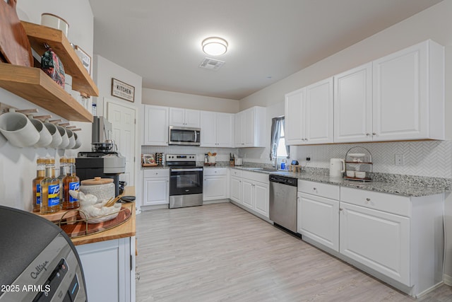 kitchen with white cabinetry, tasteful backsplash, open shelves, visible vents, and appliances with stainless steel finishes