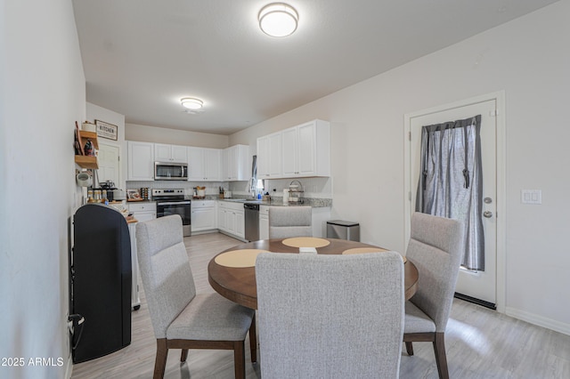 dining space featuring baseboards and light wood-style flooring