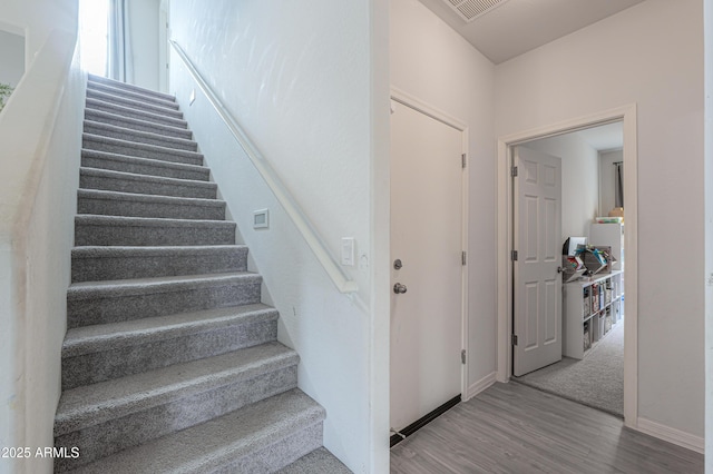 staircase with visible vents, baseboards, and wood finished floors