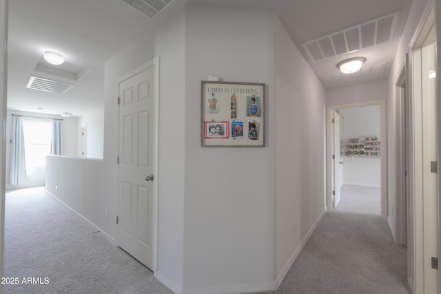 corridor with attic access, baseboards, visible vents, and carpet