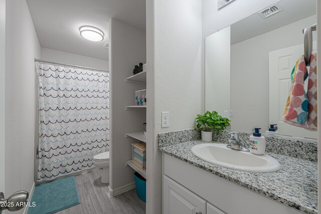 full bathroom with a shower with shower curtain, toilet, vanity, wood finished floors, and visible vents