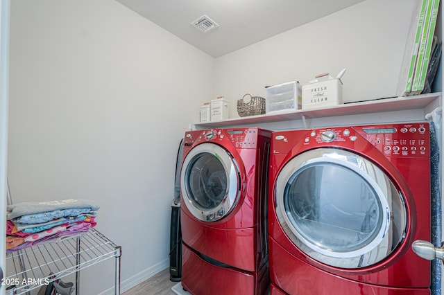 laundry room with baseboards, visible vents, washer and dryer, laundry area, and wood finished floors