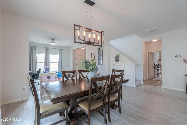 dining room with light wood-style floors, baseboards, stairway, and a chandelier