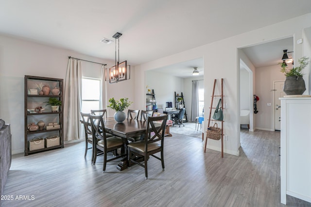 dining room with a chandelier, baseboards, light wood finished floors, and visible vents