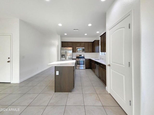 kitchen with a center island, dark brown cabinetry, sink, light tile patterned flooring, and appliances with stainless steel finishes