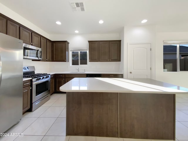 kitchen with dark brown cabinetry, sink, appliances with stainless steel finishes, and a center island