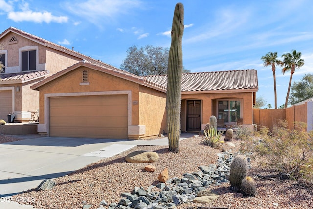 mediterranean / spanish-style home with stucco siding, concrete driveway, fence, a garage, and a tiled roof