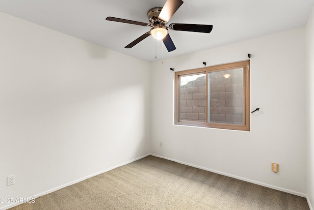 carpeted spare room featuring a ceiling fan and baseboards