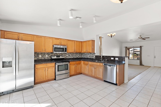 kitchen with a sink, visible vents, vaulted ceiling, appliances with stainless steel finishes, and decorative backsplash