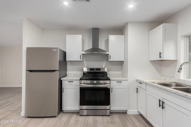 kitchen with white cabinetry, wall chimney exhaust hood, appliances with stainless steel finishes, and a sink