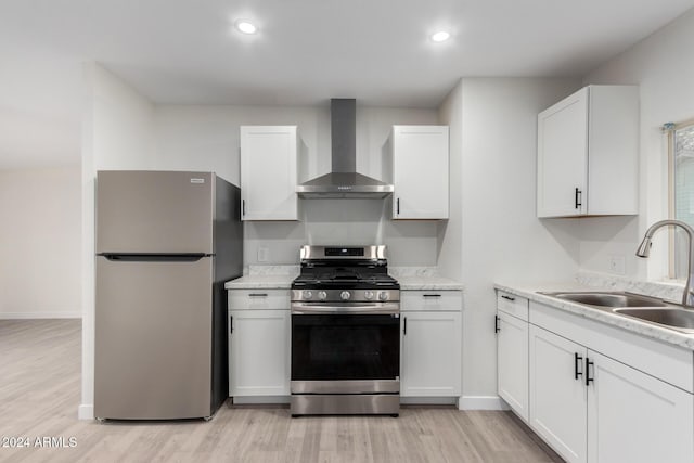 kitchen featuring a sink, wall chimney range hood, stainless steel appliances, white cabinets, and light countertops