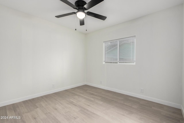 empty room with baseboards, ceiling fan, and light wood finished floors