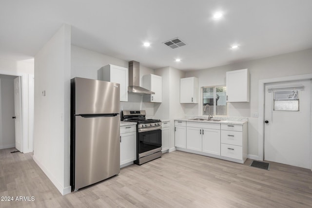 kitchen featuring visible vents, a sink, white cabinetry, stainless steel appliances, and wall chimney exhaust hood