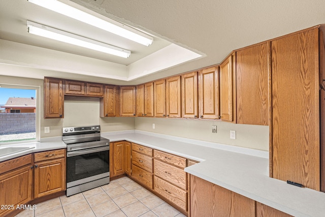 3747 W Aire Libre Ave, Phoenix, AZ 85053 - kitchen with stainless steel electric range, light tile patterned flooring, light countertops, and brown cabinets