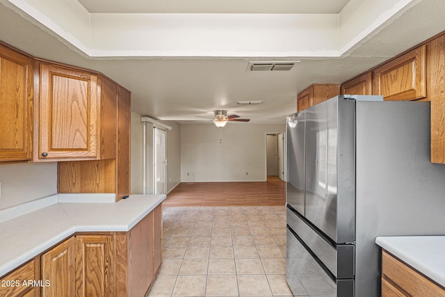 3747 W Aire Libre Ave, Phoenix, AZ 85053 - kitchen with freestanding refrigerator, light tile patterned floors, brown cabinetry, ceiling fan, and light countertops