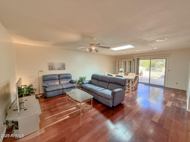 living room with hardwood / wood-style flooring, a skylight, and ceiling fan