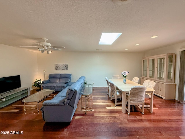 dining room with wood-type flooring, a textured ceiling, a skylight, and ceiling fan