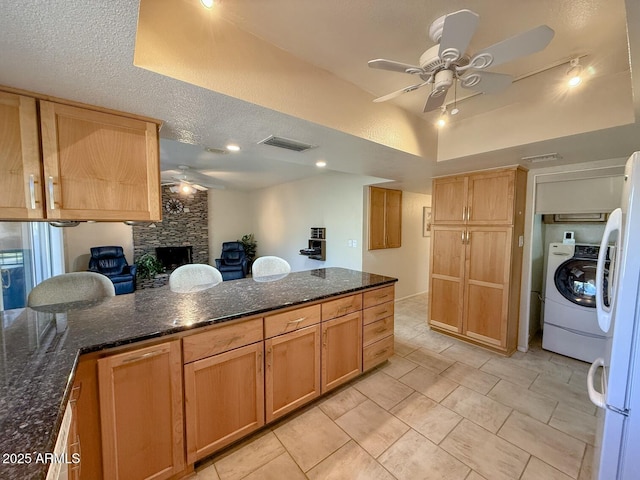 kitchen with ceiling fan, white refrigerator, dark stone counters, and independent washer and dryer