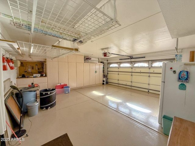 garage featuring white refrigerator and a garage door opener