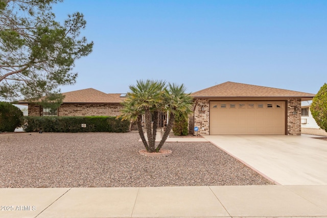 ranch-style home with a garage, concrete driveway, brick siding, and a shingled roof