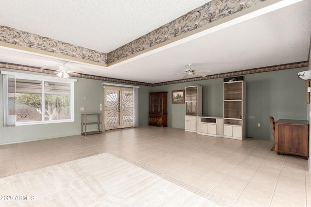 unfurnished room featuring a tray ceiling, ceiling fan, a textured ceiling, and light tile patterned floors