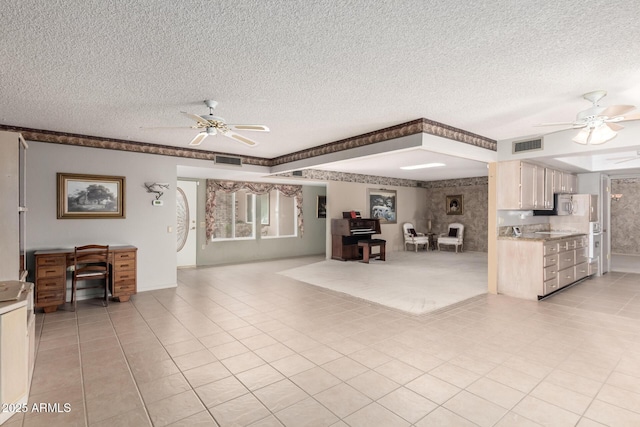 living room with ceiling fan, visible vents, and a textured ceiling