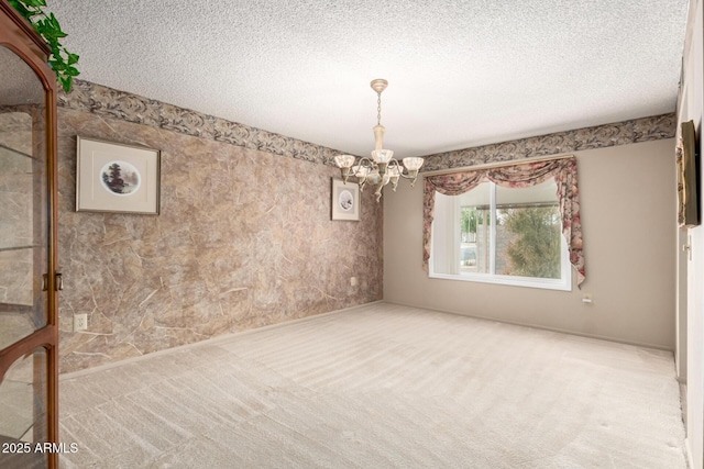 carpeted spare room with a textured ceiling and a chandelier