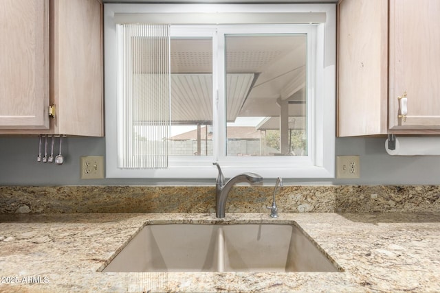 details featuring a sink and light stone countertops