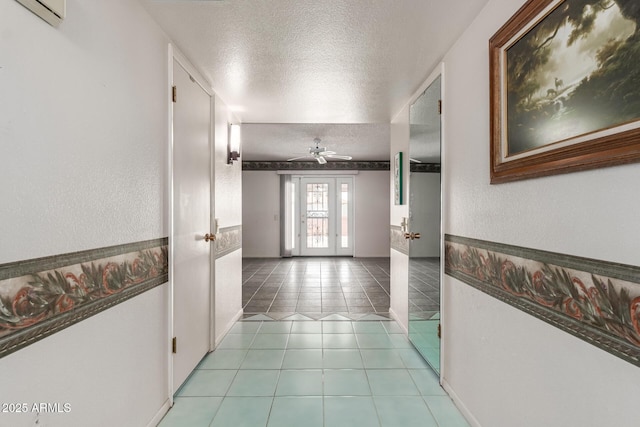 hall featuring french doors, a textured wall, tile patterned flooring, an AC wall unit, and a textured ceiling