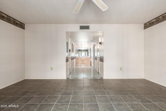 tiled spare room with a ceiling fan, visible vents, and a textured ceiling