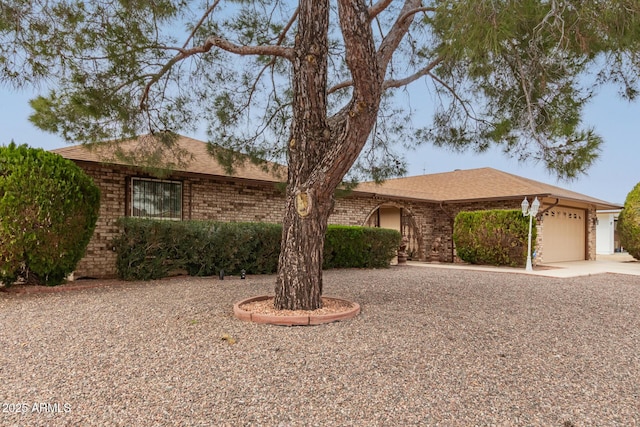 ranch-style home featuring a garage, driveway, brick siding, and a shingled roof