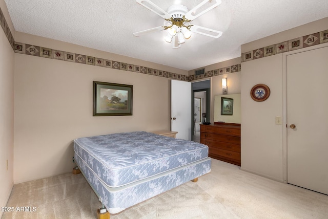 carpeted bedroom featuring a textured ceiling, visible vents, and a ceiling fan