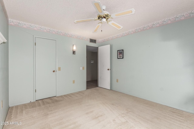 unfurnished bedroom featuring a textured ceiling, ceiling fan, carpet, and visible vents