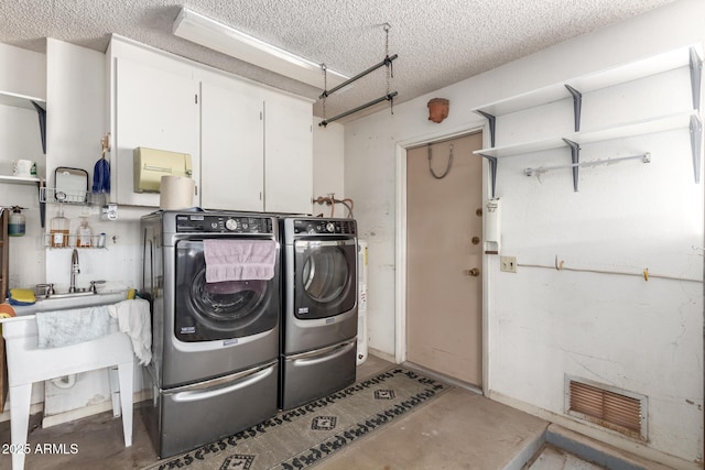 clothes washing area with laundry area, visible vents, a textured ceiling, and washing machine and clothes dryer