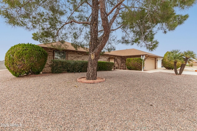 single story home featuring a garage, driveway, and brick siding