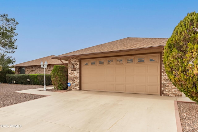 ranch-style home with brick siding, roof with shingles, and an attached garage