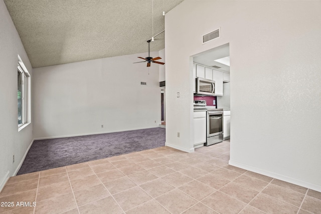 unfurnished living room featuring ceiling fan, light colored carpet, a textured ceiling, high vaulted ceiling, and visible vents