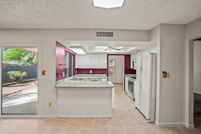 kitchen with a sink, white appliances, a peninsula, light tile patterned floors, and visible vents