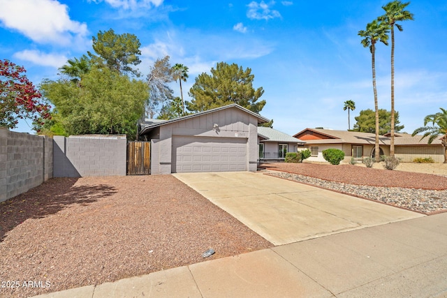 view of front of property with an attached garage, a gate, fence, and driveway