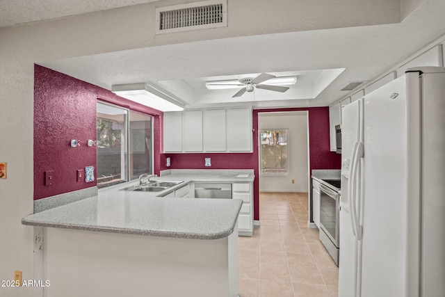 kitchen with a sink, white refrigerator with ice dispenser, white cabinetry, a tray ceiling, and visible vents