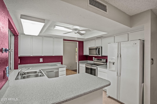 kitchen with visible vents, appliances with stainless steel finishes, a sink, light countertops, and a peninsula