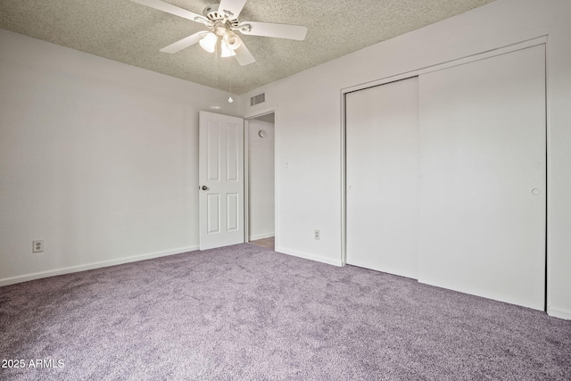 unfurnished bedroom with ceiling fan, a textured ceiling, visible vents, carpet floors, and a closet
